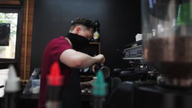 Koruyucu maskeli adam kafeteryada lezzetli bir kahve hazırlıyor.
