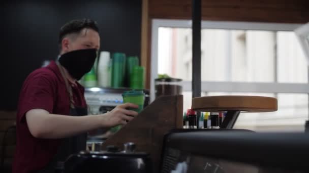 戴面具的巴里斯塔把一杯咖啡放在小木桌上 — 图库视频影像