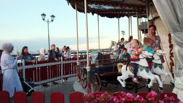 Ouders met kleine kinderen rijden carrousel in pretpark — Stockvideo