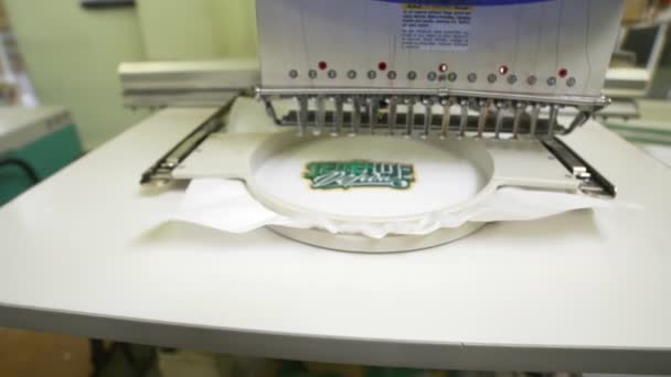 Maszyna haftuje words Zielony Derby na białym arkuszu tkaniny — Wideo stockowe