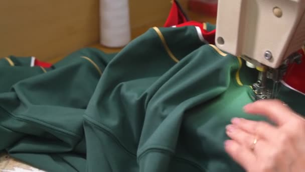 Женщина шьет новую хоккейную форму из темно-зеленой ткани в магазине — стоковое видео