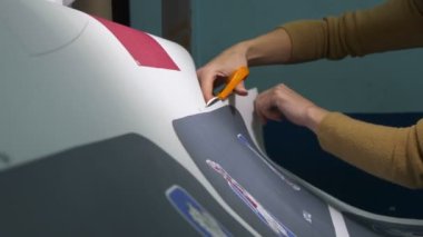 İşçi, hokey takımının logolarının kalıplarıyla kağıt kesiyor.