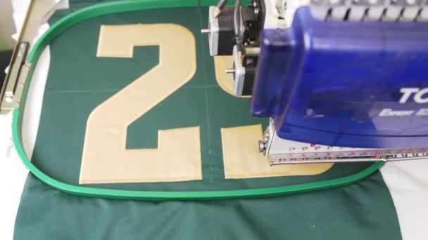 Moderní automatický obráběcí stroj šije číslo na zelenou tkaninu