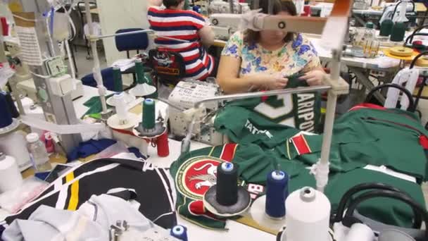 Kvinnlig arbetare syr ny hockey uniform av grönt tyg — Stockvideo