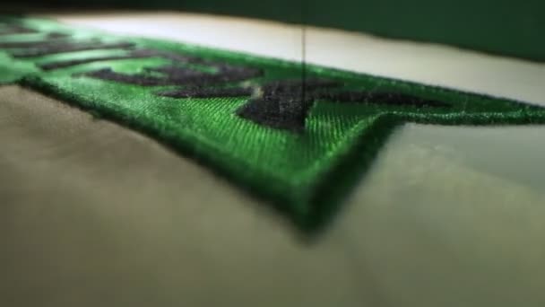 Machine embroiders company logo on green fabric in shop — Stock Video