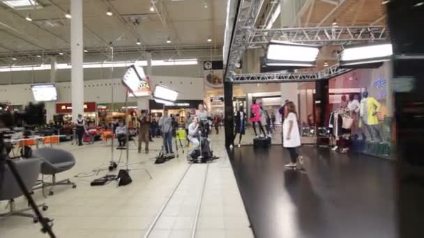 Cameraman pousse femme prenant part au défilé de mode dans le centre commercial — Video