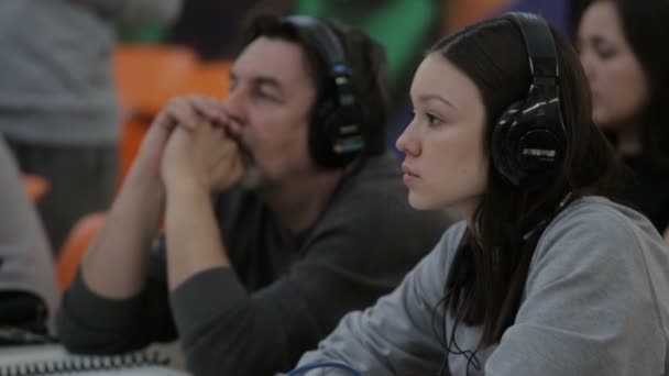 Director de cine con equipo en auriculares se sienta a la mesa en el centro comercial — Vídeos de Stock