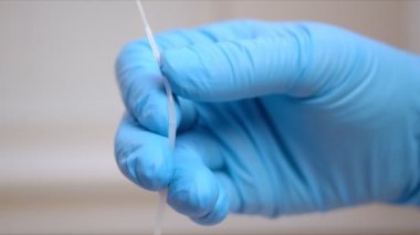 Hemşire pamuk çubuğunu coronavirus numunesiyle büker.
