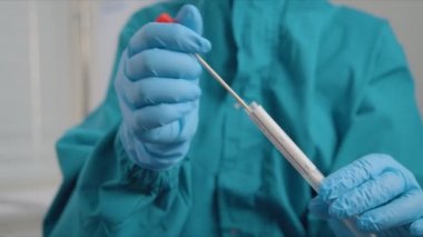 Takım elbiseli doktor, tüp içine sürme numunesi koyuyor.