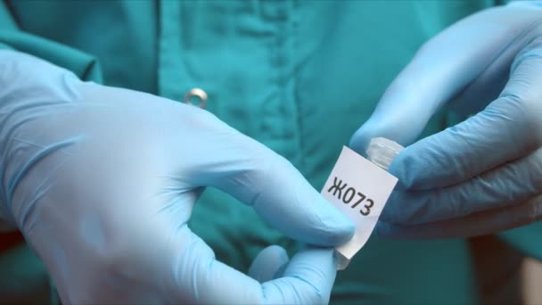 Homem cola marcador no tubo com amostra para teste de coronavírus — Vídeo de Stock