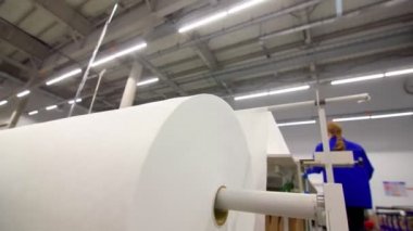 Kesme masası ve kadının yanında büyük bir yuvarlak beyaz tomar.