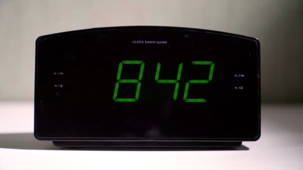 Digitale klok toont tijd met gloeiende groene cijfers op tafel — Stockvideo