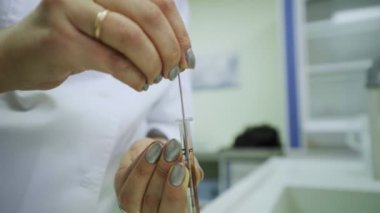 Kadın laboratuardaki damıtma aracına test malzemesi koyuyor.