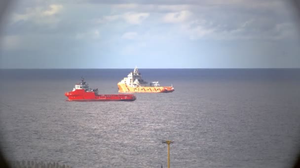 Rode en gele tankers drijven onder bewolkte lucht op oceaanwater — Stockvideo