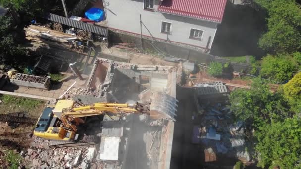 Yellow excavator destroys wall of abandoned cottage at block — Stock Video