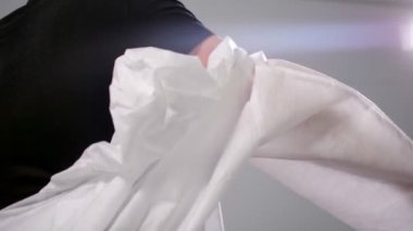 Adam tek kullanımlık koruyucu takım elbise giyer.