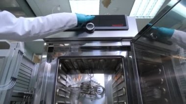 Bilimadamı laboratuvarda makinenin kapısını kapatmak için tuşa basıyor