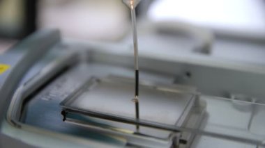 Araştırmada sürgülü cama mikroskopla yağ damlatıyor.