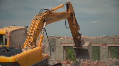 Sarı kazıcı, eski binanın tuğla duvarını tahrip etti.