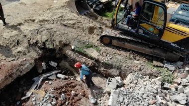 İşçiler köydeki kazıcının yakınındaki delikten enkazı temizliyorlar.