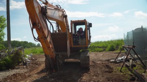 Trabalhador dirige escavadeira lagarta ao longo do local de demolição — Vídeo de Stock