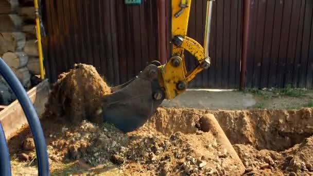 Excavatrice creuse une tranchée près de la clôture dans la cour de la maison de village — Video
