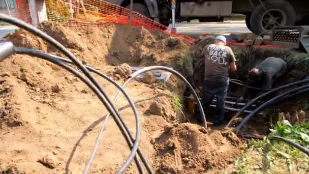 Werknemers installeren metalen buis om draden staande in loopgraaf lopen — Stockvideo