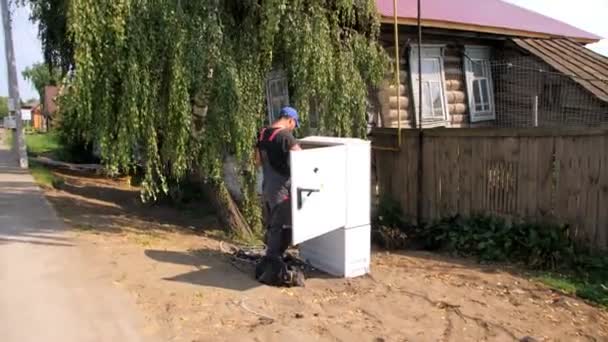 Homme travaille avec l'équipement dans la boîte de commutation sur la rue du village — Video