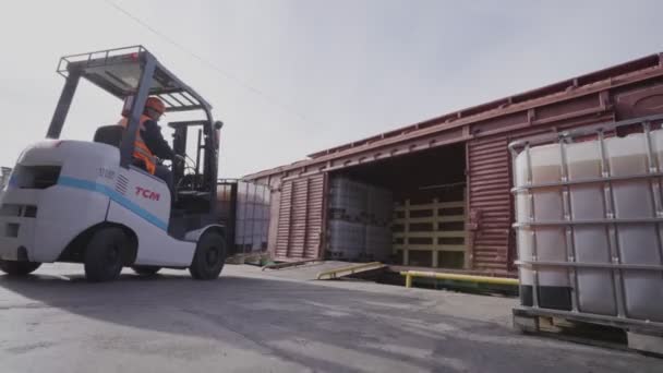 Вилочный погрузчик перевозит контейнер в металлическую коробку вдоль двора — стоковое видео