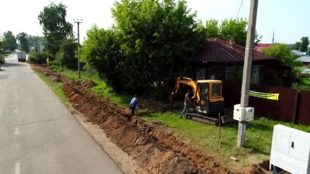 掘削機を持つ労働者は村で電気ケーブルを走らせる — ストック動画