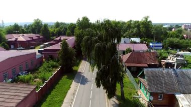 Yeşil ağaçların arasında binalar olan büyük köyün karşısındaki yol