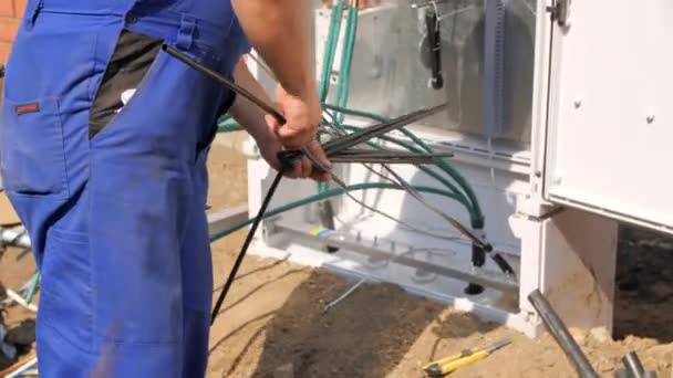 Werknemer zet isolatie op draden in schakelkast in straat — Stockvideo