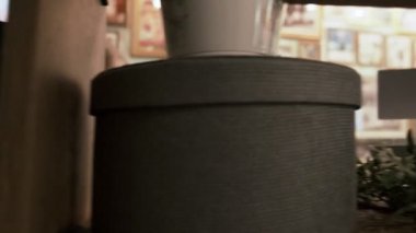 Sarışın kadın, kafeteryadaki çiçeklerle dolu raftan kitap alıyor.