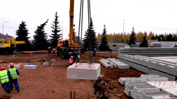 Grúa transporta bloque de cemento bajo control de los empleados — Vídeos de Stock