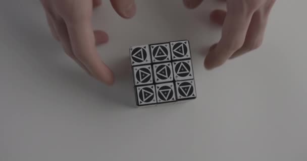 Ο άνθρωπος γίνεται ασυνήθιστος κύβος Rubik με τρίγωνα πάνω από το τραπέζι — Αρχείο Βίντεο