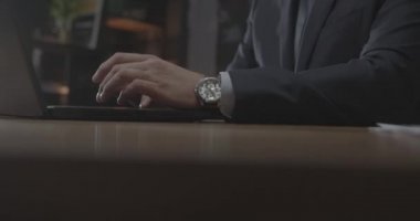 Kostüm giyen eleman masadaki çağdaş dizüstü bilgisayarda çalışıyor.