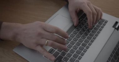 İş yerinde yakın planda oturan kişi dizüstü bilgisayarda tuşlara basar