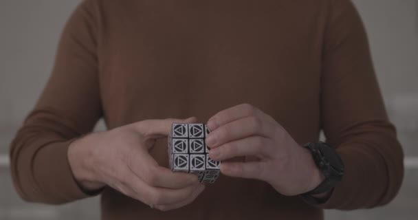 Mannen i bruna kläder löser Rubik pussel i kontor närbild — Stockvideo