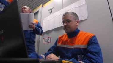 Alt istasyonda dizüstü bilgisayarı olan elektrikçiler kontrol ediyor.