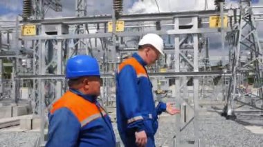 Elektrikçiler elektrik dağıtım istasyonunda yürürler