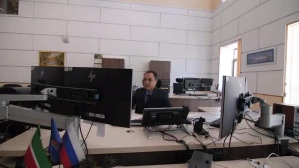 Security guard works on computer sitting at table in office — Stock Video