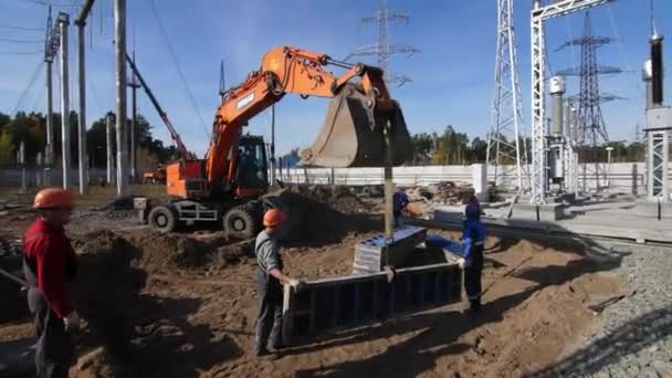 Les hommes tiennent la plaque de béton accrochée sur le godet de la pelle sur le site — Video