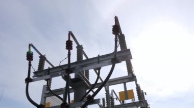 Bulutlu gökyüzü altındaki desteklerde kablo yolu boruları ve izolatörler