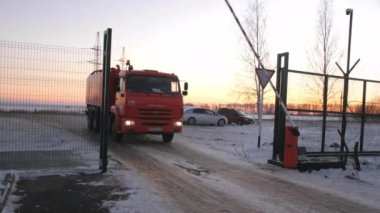 Kırmızı itfaiye aracı karlı yol boyunca açık kapıdan geçiyor.