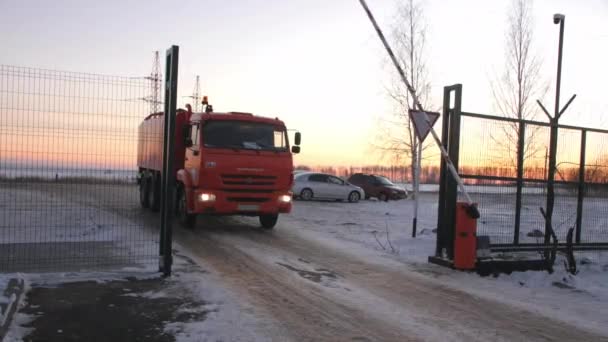 Красная пожарная машина проезжает через открытые ворота вдоль заснеженной дороги — стоковое видео