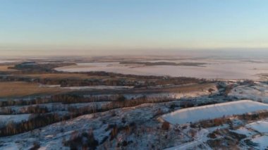Ağaçları ve arıtma istasyonunun yakınındaki tarlaları olan karlı tepeler.