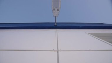 Açık gökyüzünün altındaki depo binasının mavi duvarında öndeki lamba