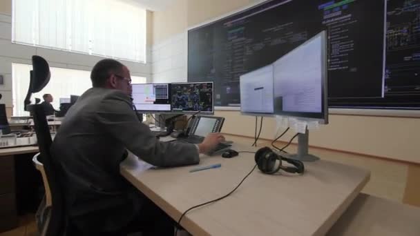 Operador termina conversación cerca de monitores en sala de control — Vídeo de stock
