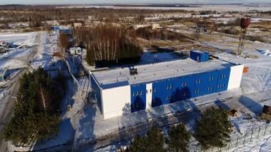 Gün batımında uzak ormanlara karşı çatısı karlı bir bina.