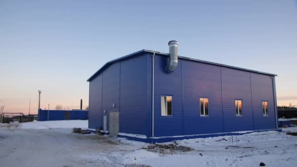 Blue workshop with chimney on snowy ground at sunset — 图库视频影像